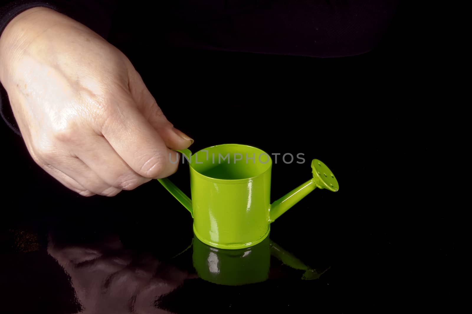 Female hand holding a watering can in front of a chalkboard