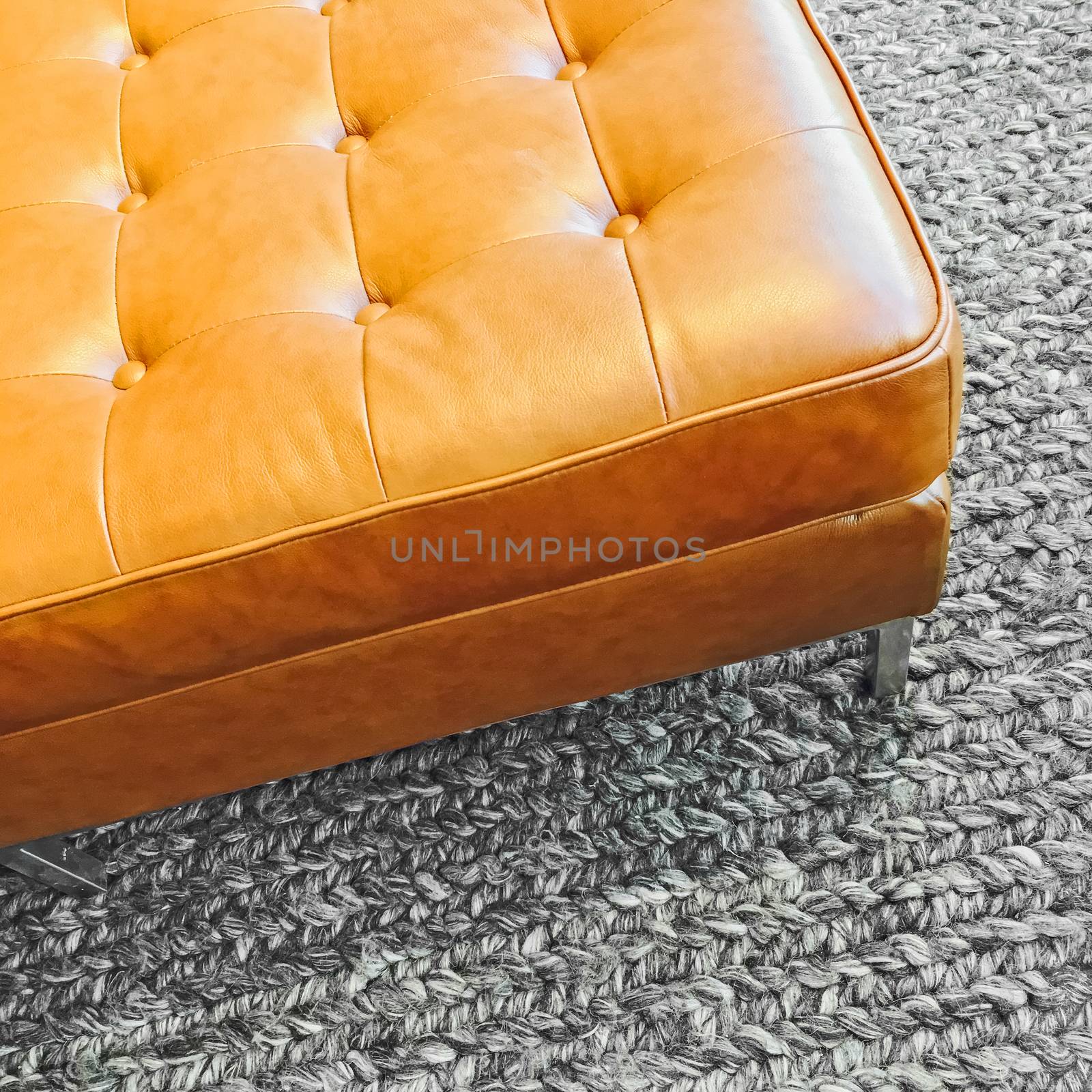 Fashionable leather seat on knitted wool carpet. Contemporary design.