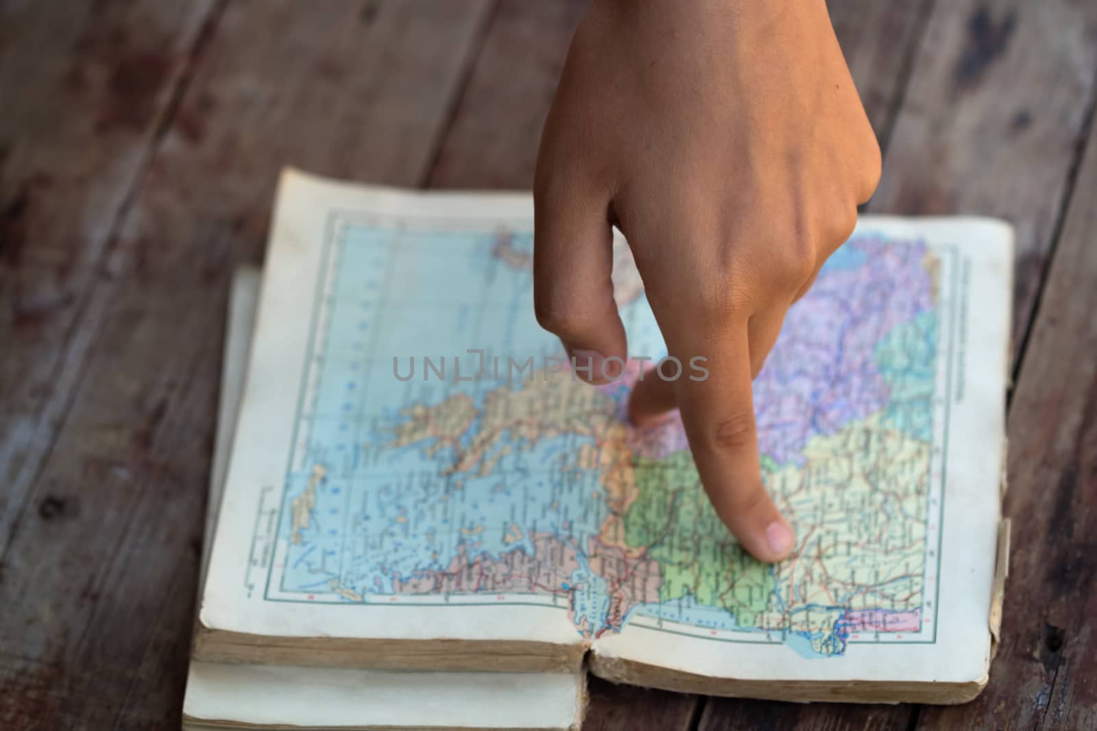 Fingers walking on the map in an old book. Selective focus image. Creative travel, hiking or geography learning concept