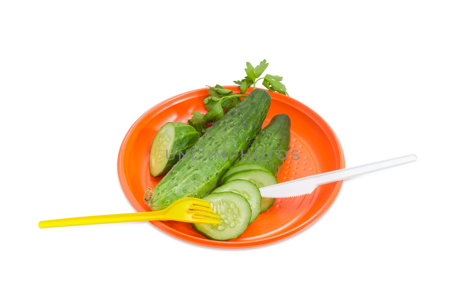 Orange disposable plastic plate, whole and sliced cucumbers with disposable plastic fork and knife on it on a light background
