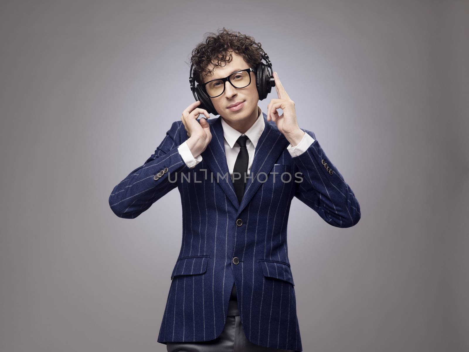 Funny man in headphones listening music, studio shot on gray background