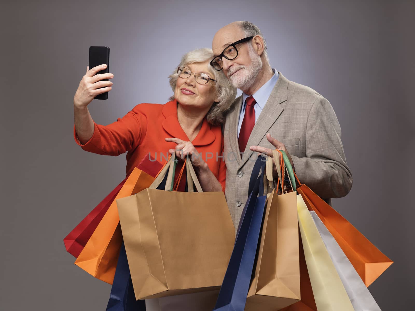 Happy couple taking selfie after shopping with many bags