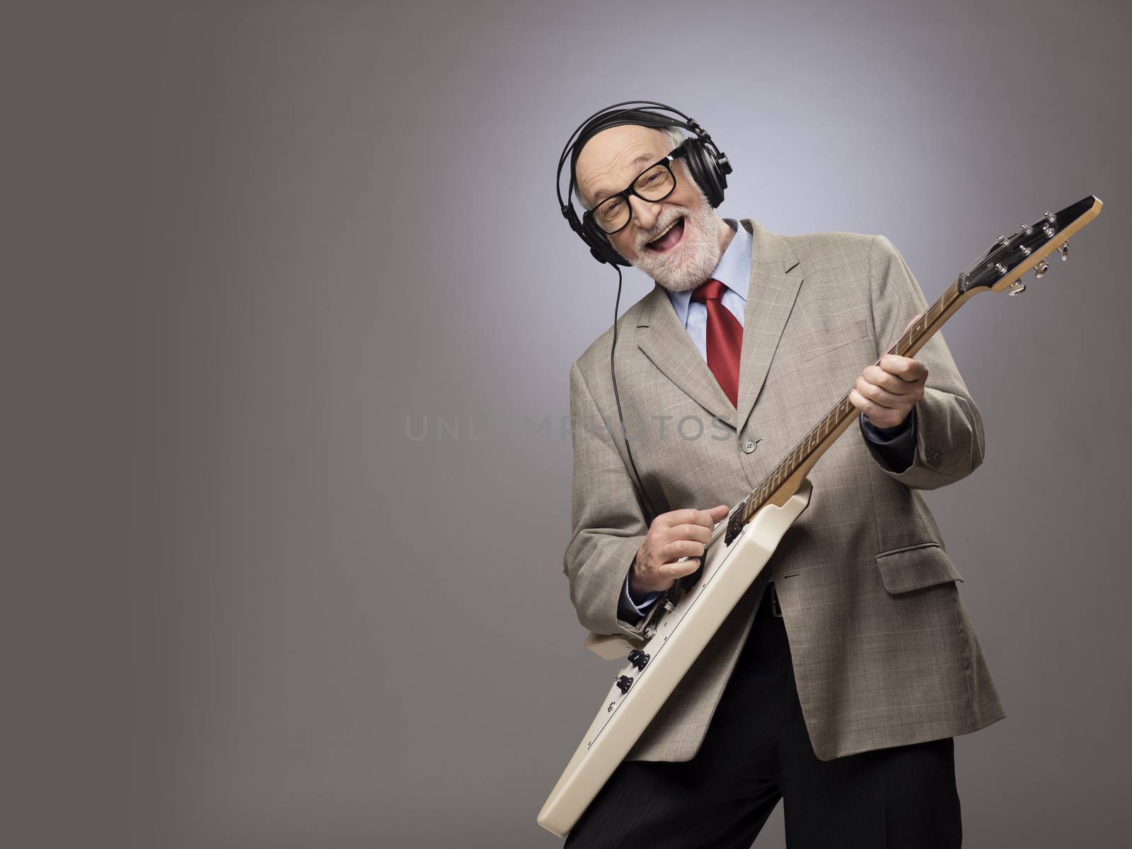 Happy funny senior man playing electric guitar