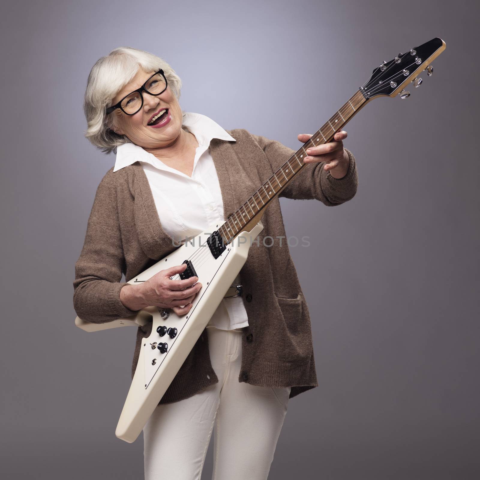 Senior woman playing electric guitar by ALotOfPeople