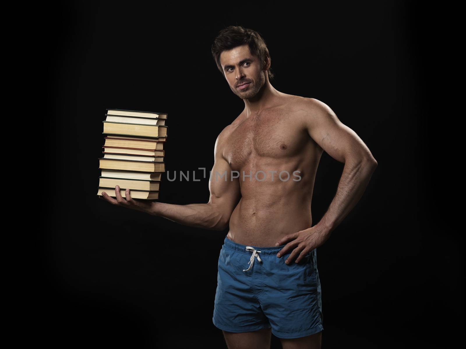 Knowledge is power concept, strong muscular man holding stack of books