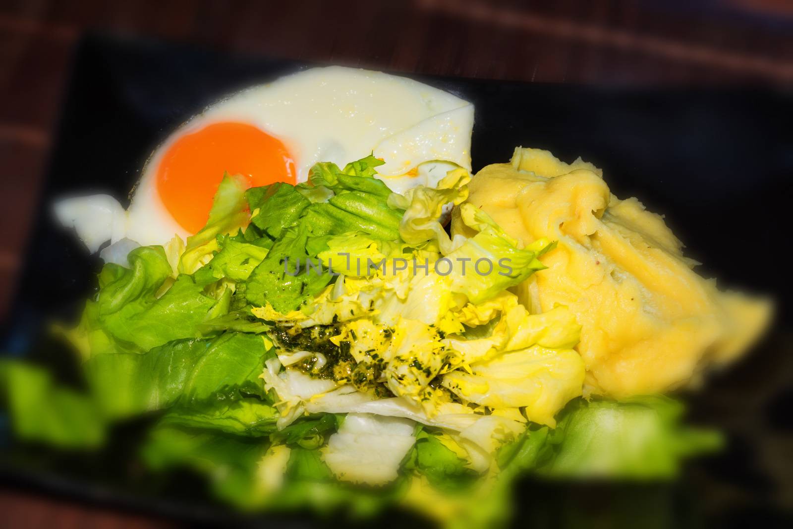 Fried egg in round shape on a white bread toast and black plate.