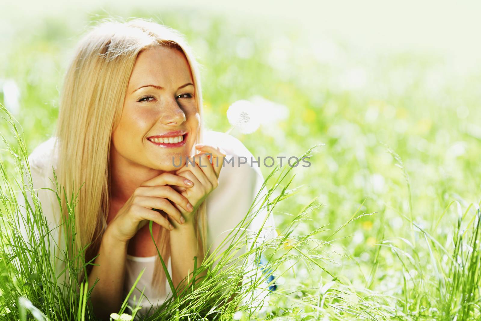 girl with a dandelion in his hand lying on the grass