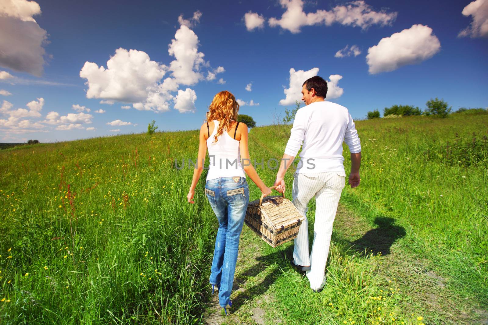 man and woman walk on picnic in green grass