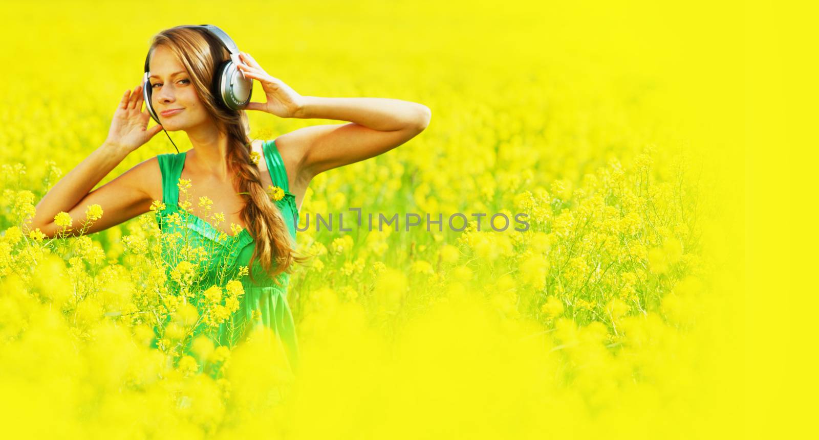 Girl listening to music on oilseed field