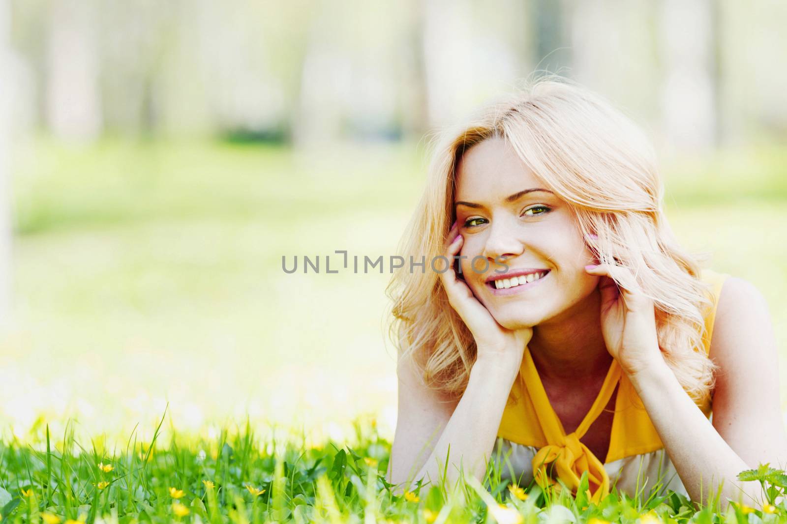Smilng happy young woman lying on green grass meadow