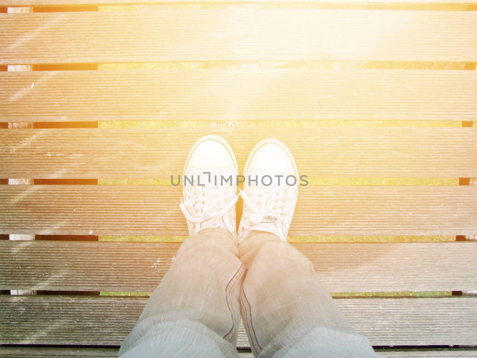 Selfie of woman white sneaker shoes stand on wooden bridge background with copy space, top view