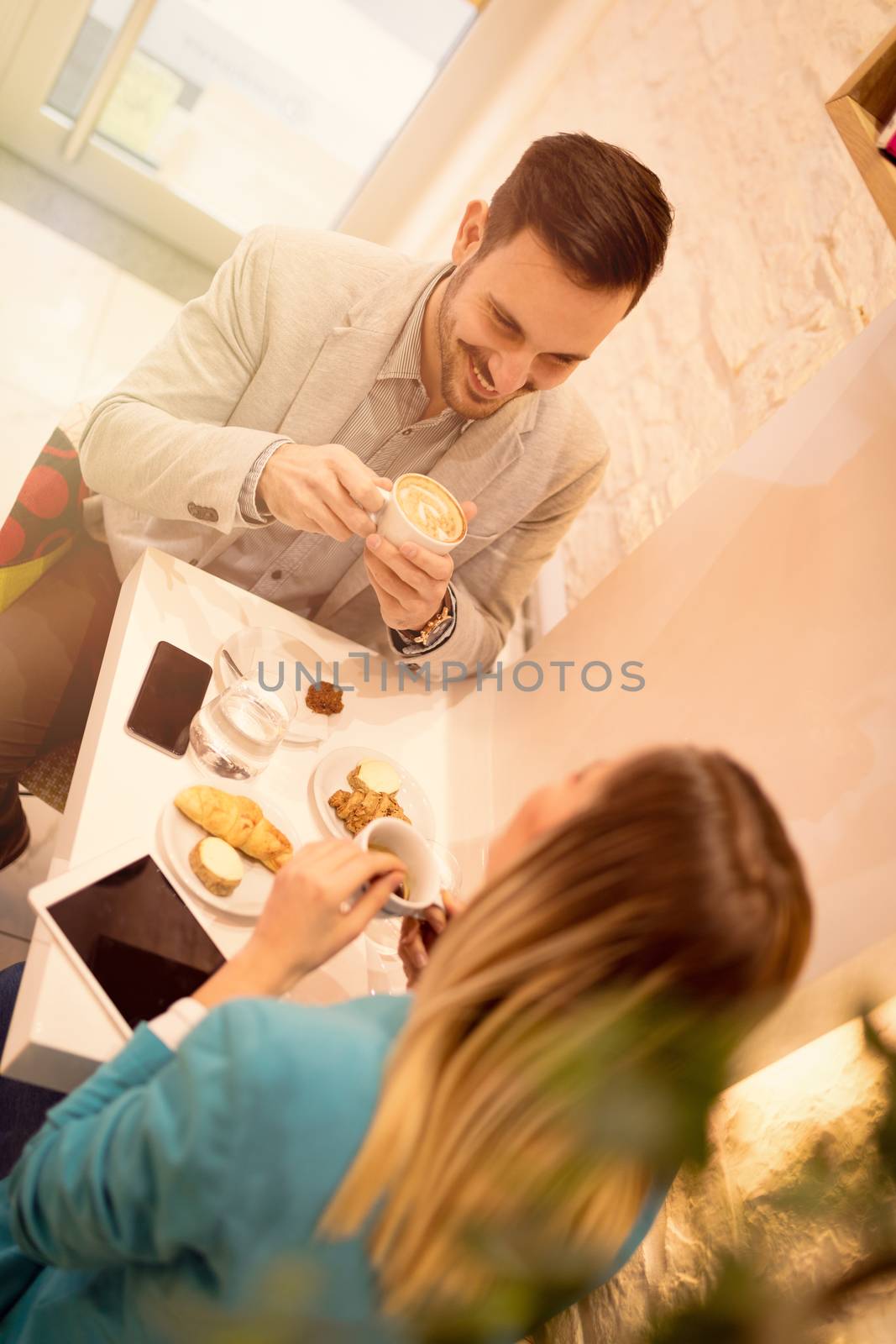 Young smiling businesspeople on a break in a cafe. They are drinking coffee and talking with smile. Selective focus.