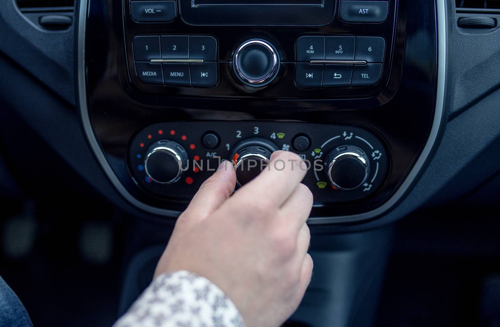 male hand pressing button in modern car. Man adjusts the temperature of the car air conditioner