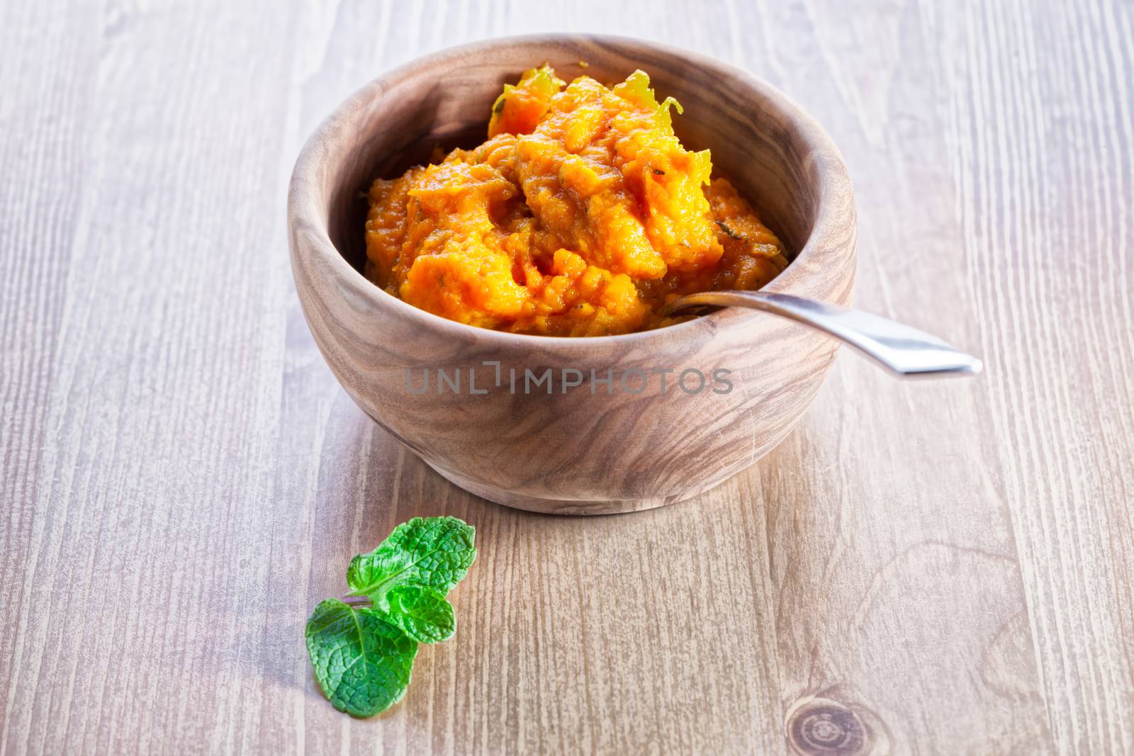 Pumpkin puree with greenery served on a wooden surface