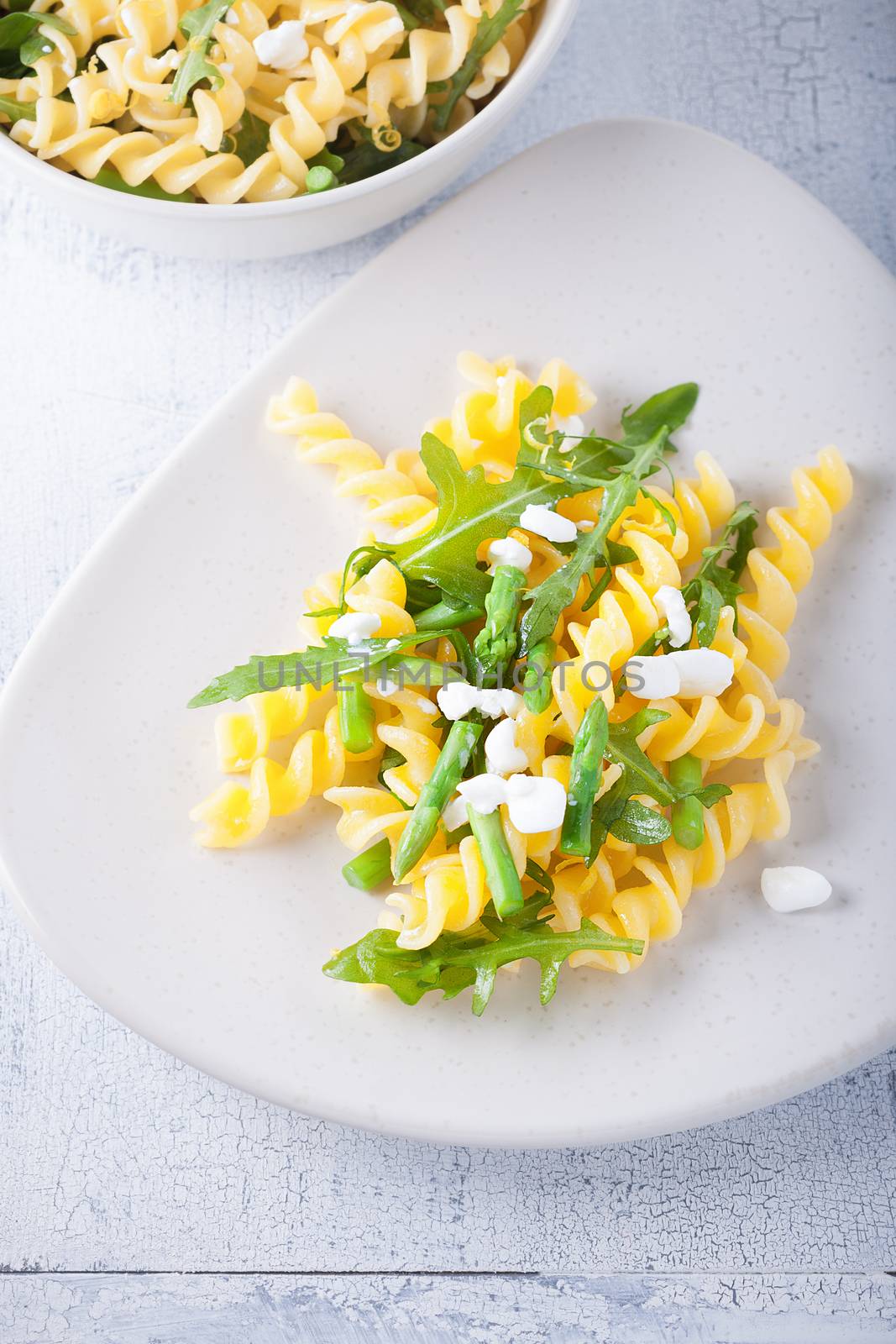 Pasta salad with asparagus and arugula on a white plate