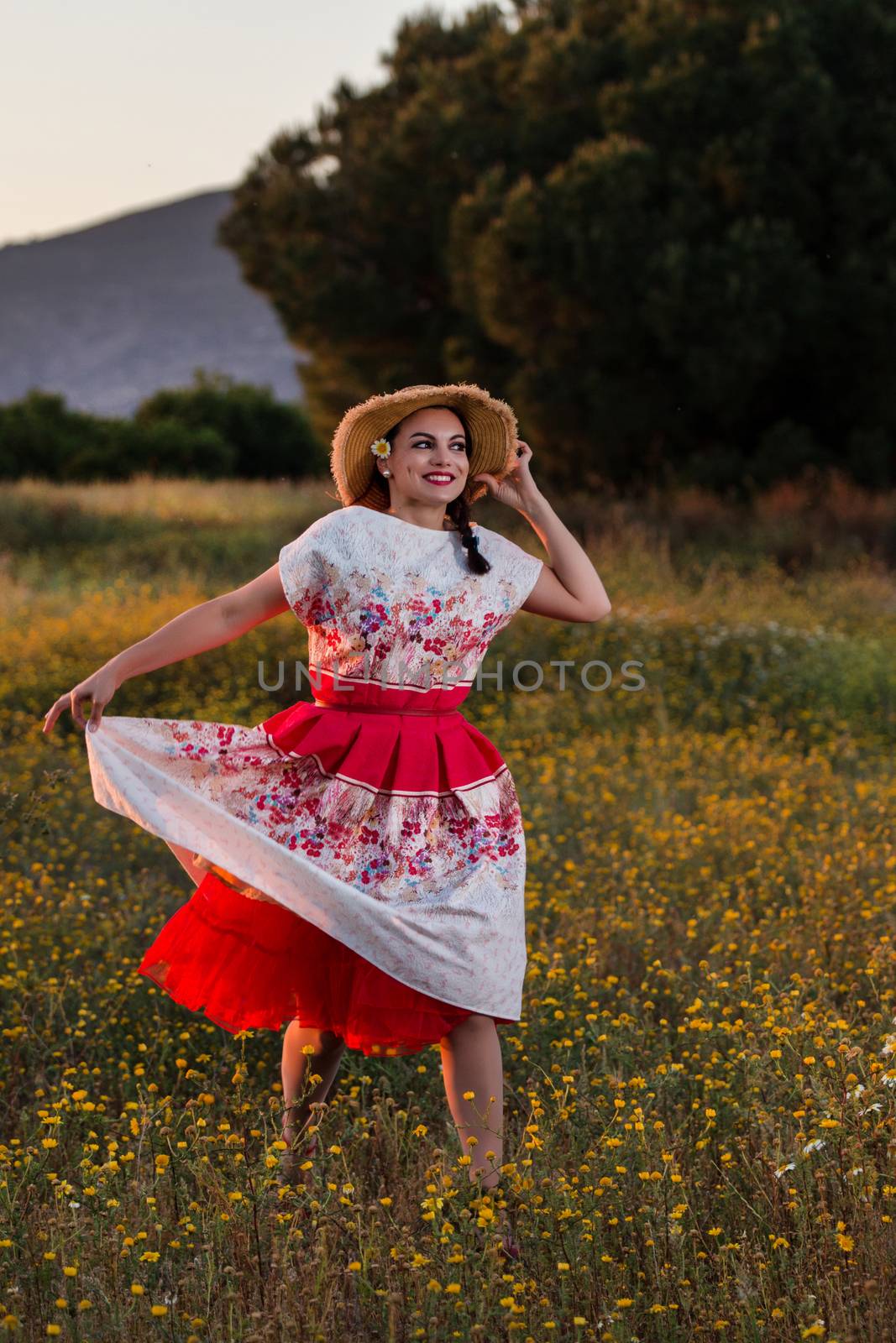 Vintage girl on the countryside with wicker hat on a flower field.