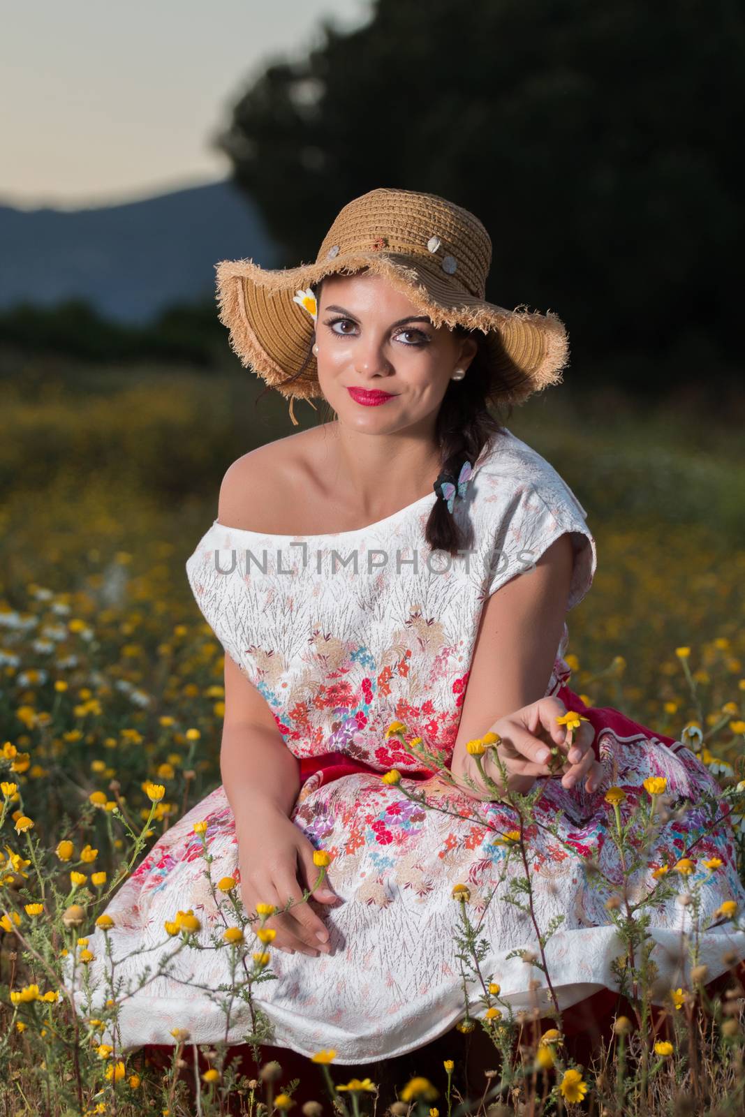 Vintage girl on the countryside with wicker hat on a flower field.