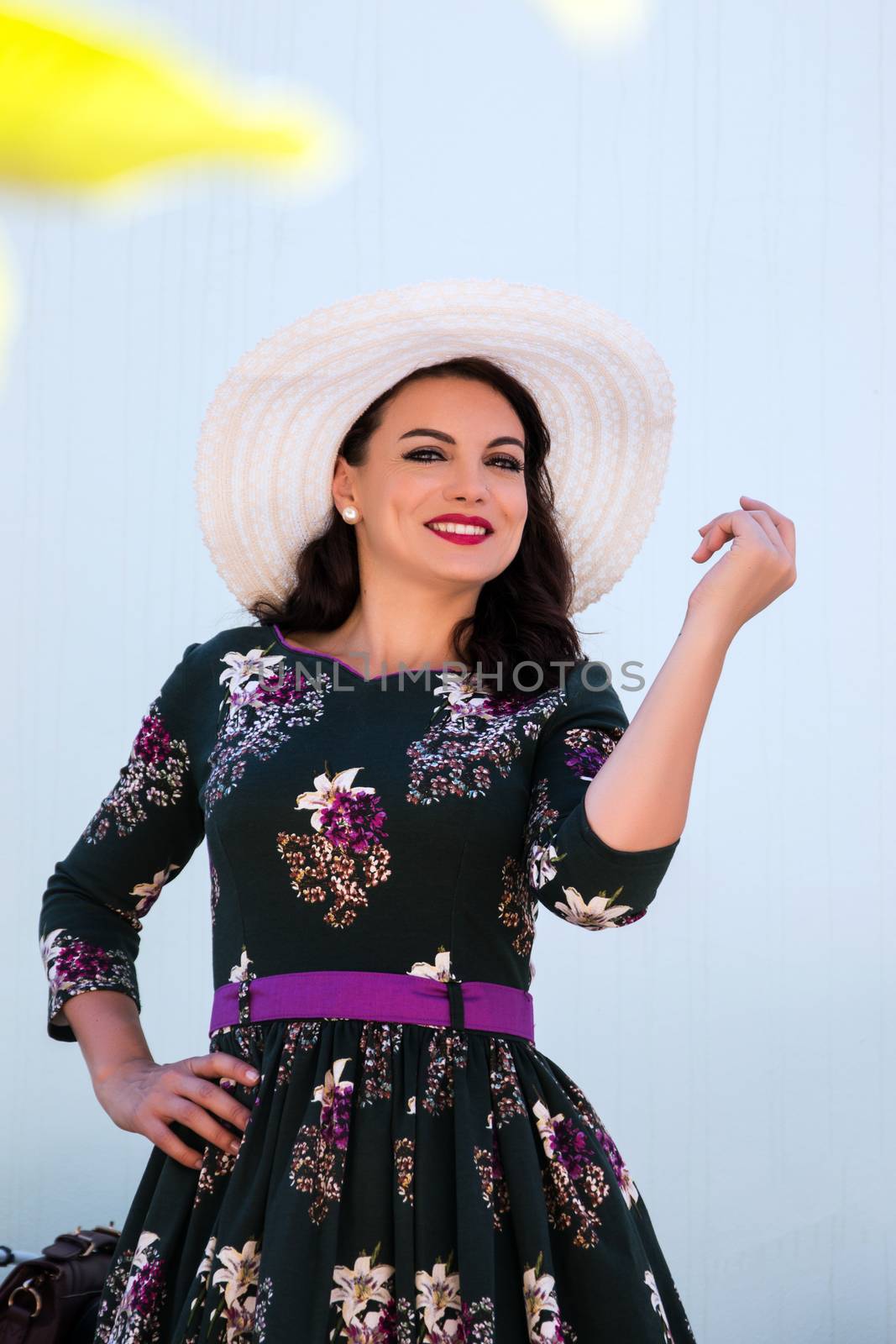 Vintage girl with beautiful floral dress with a white hat.