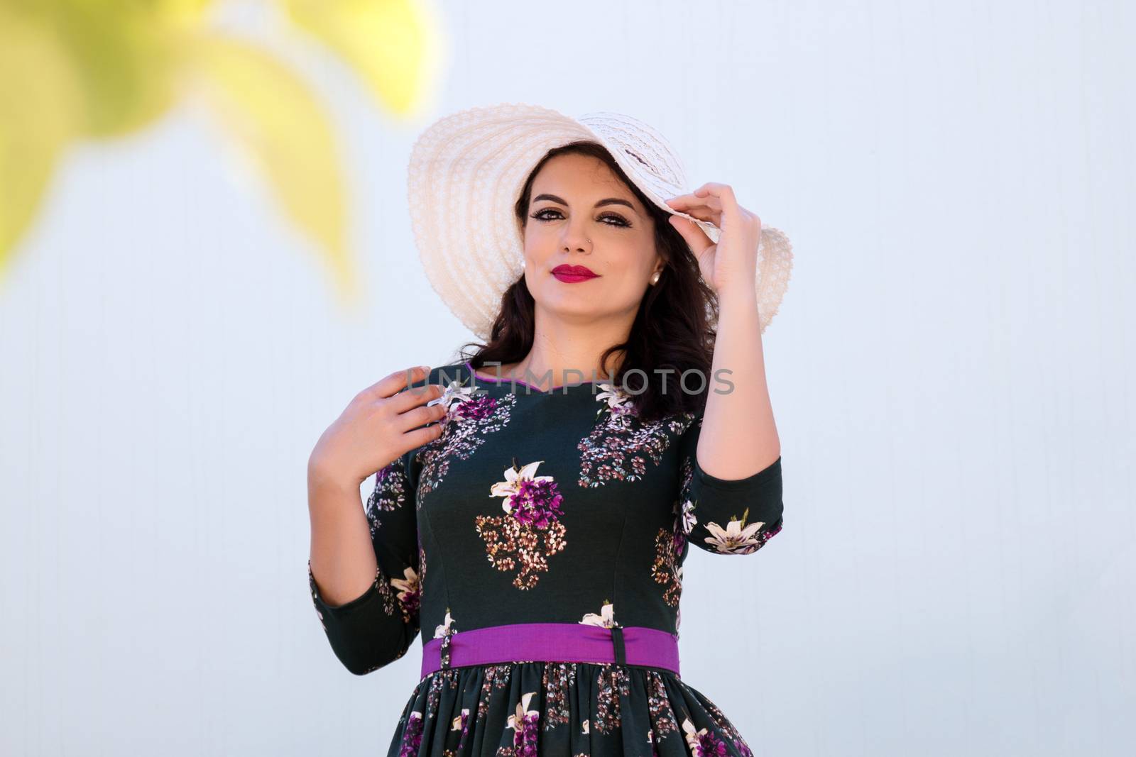 Vintage girl with beautiful floral dress with a white hat.