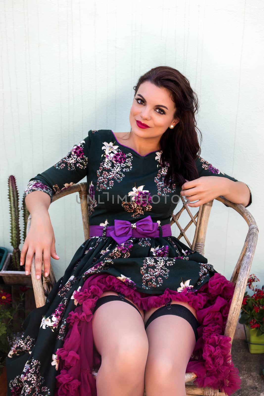 Vintage girl with floral dress posing on a wooden chair.