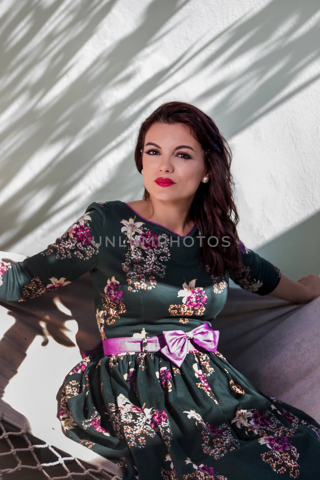 Vintage girl with floral dress relaxing on hammock.