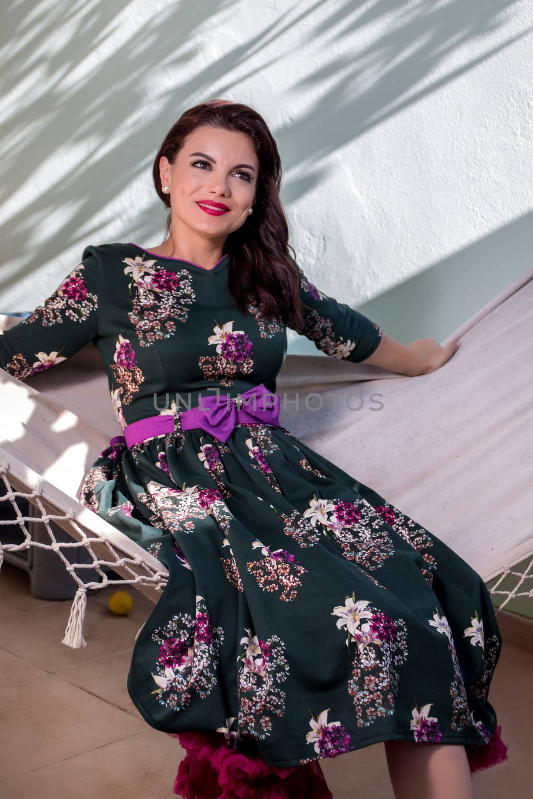 Vintage girl with floral dress relaxing on hammock.