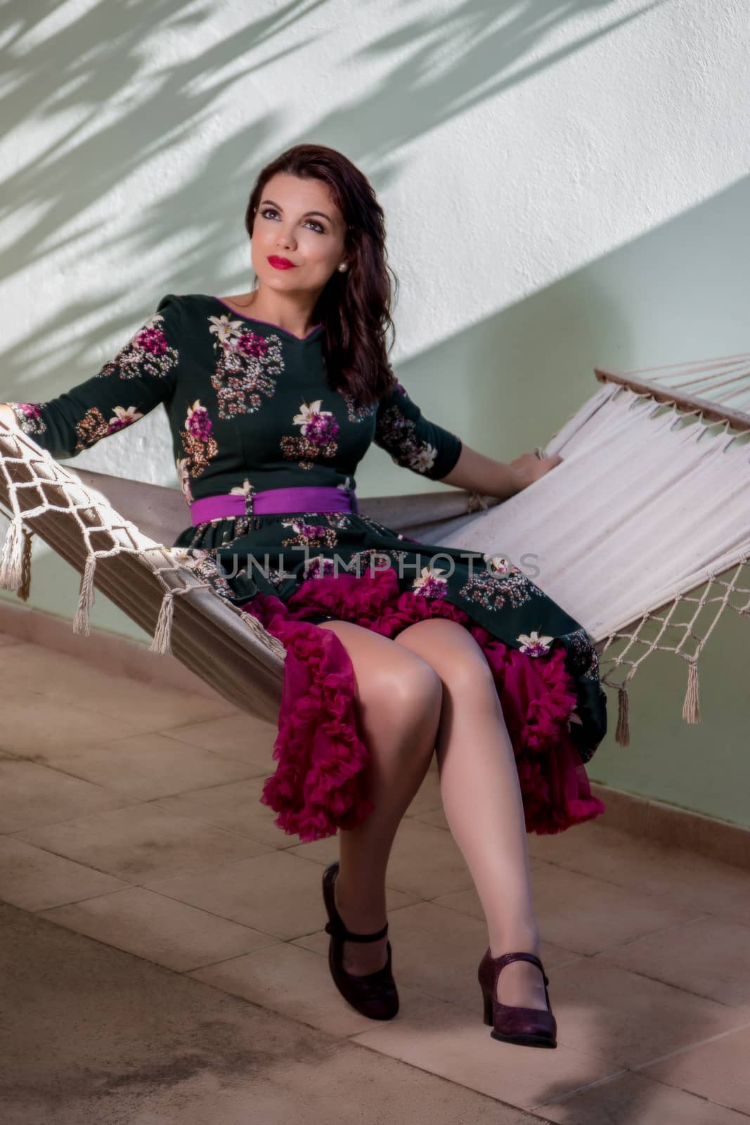 Vintage girl with floral dress relaxing on hammock.