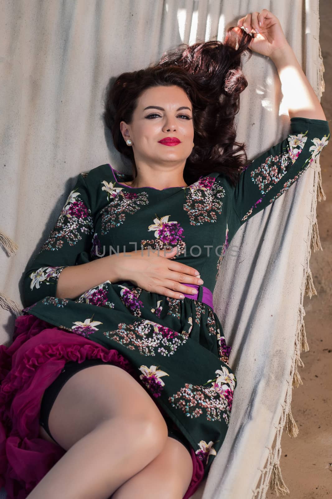 Vintage girl with floral dress relaxing on hammock.