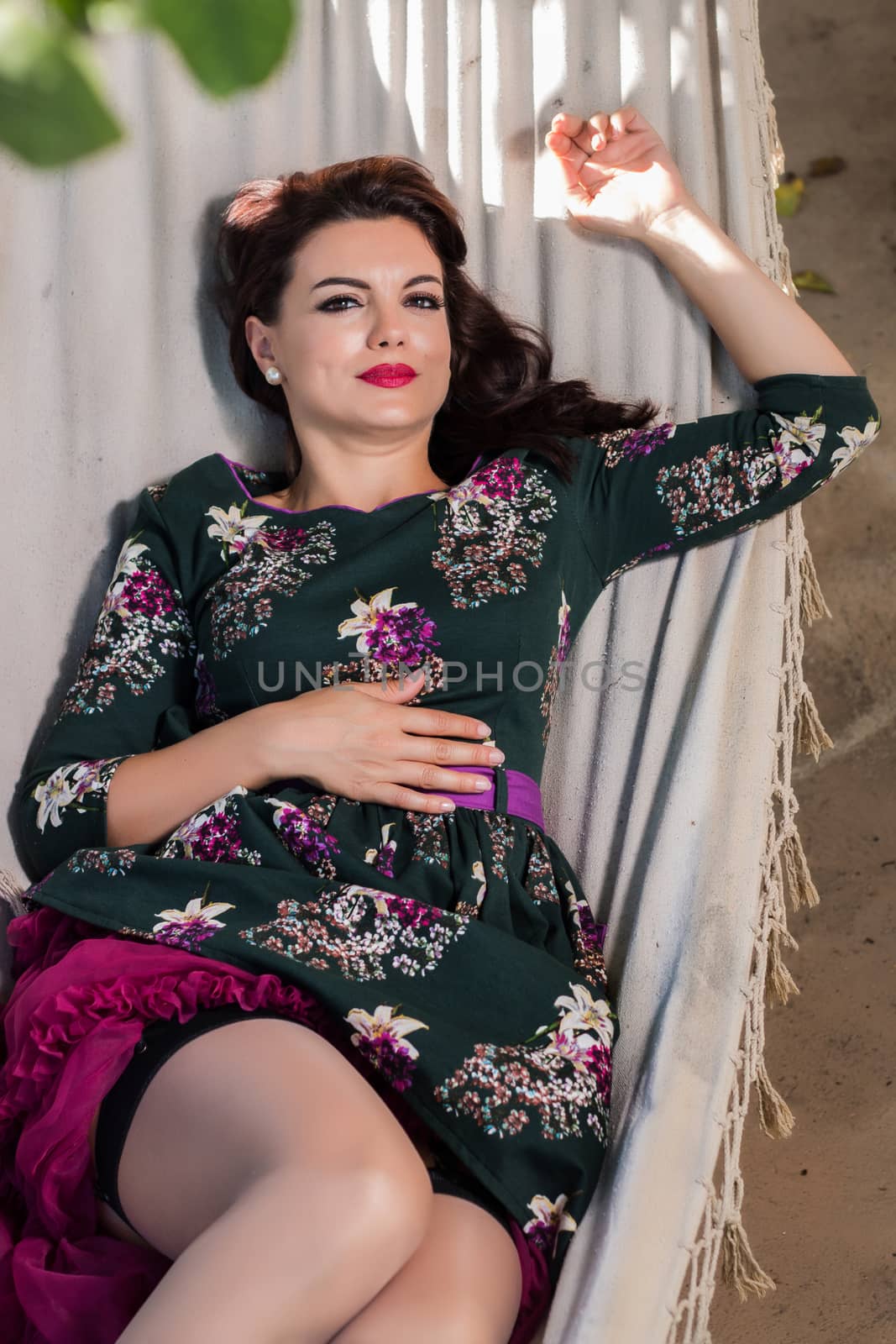 Vintage girl with floral dress relaxing on hammock.