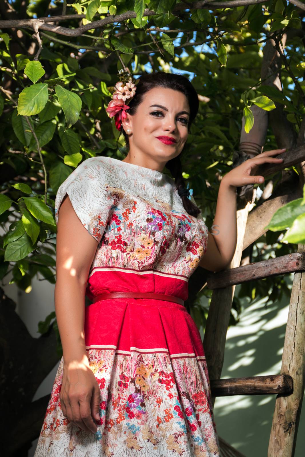 Vintage girl with floral dress climbing a lemon tree.