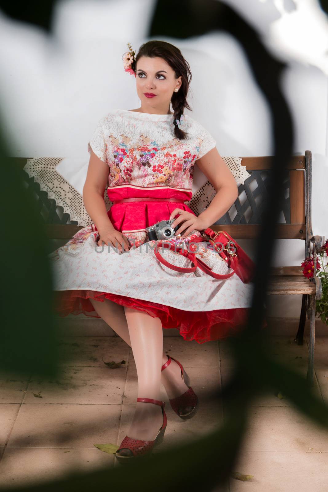 Vintage girl with floral dress relaxing on a park bench.