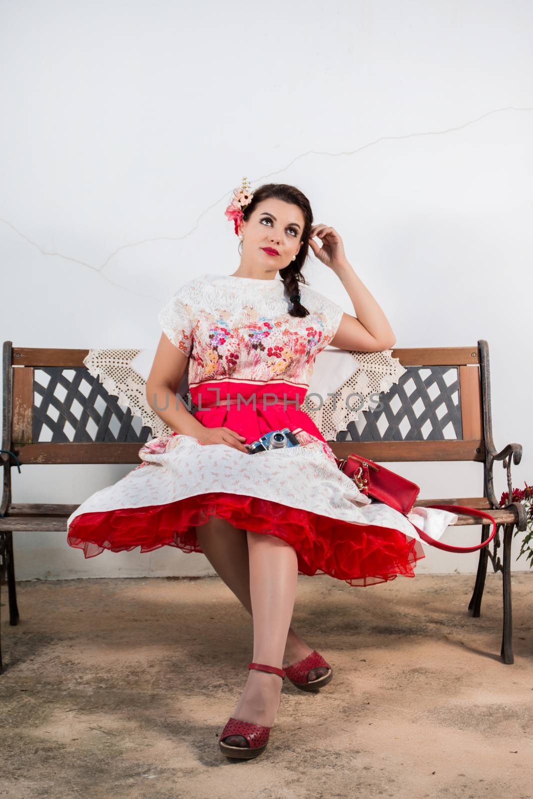 Vintage girl with floral dress relaxing on a park bench.