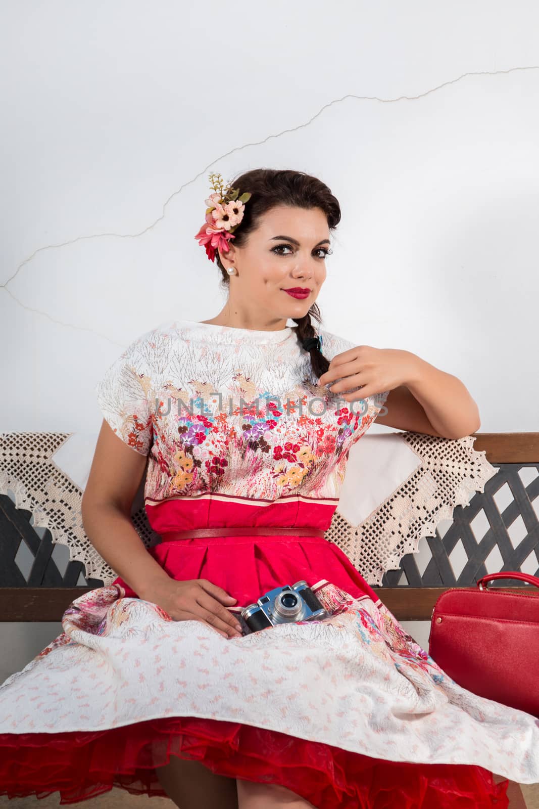 Vintage girl with floral dress relaxing on a park bench.