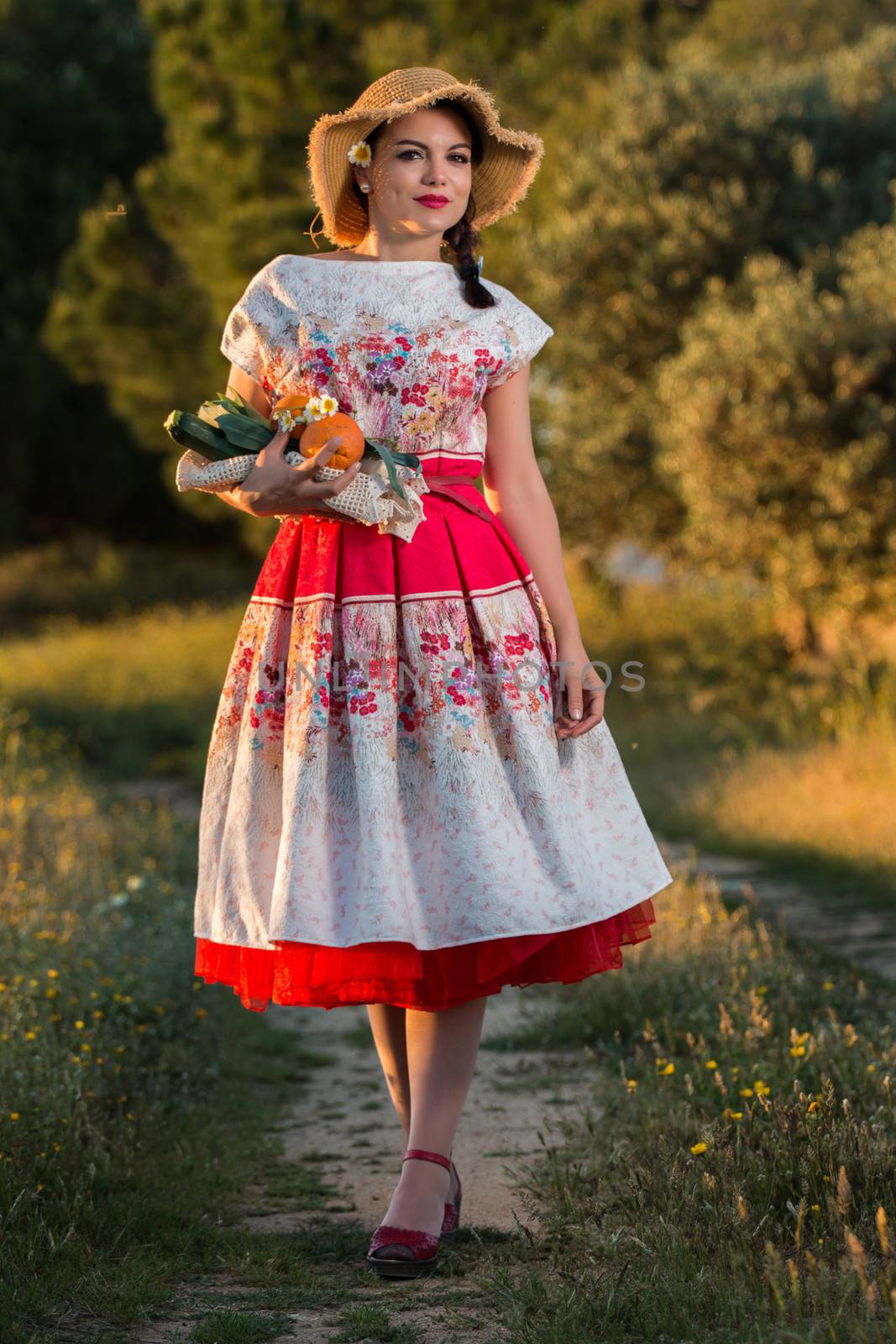 Vintage girl on the countryside with wicker hat gathering groceries.