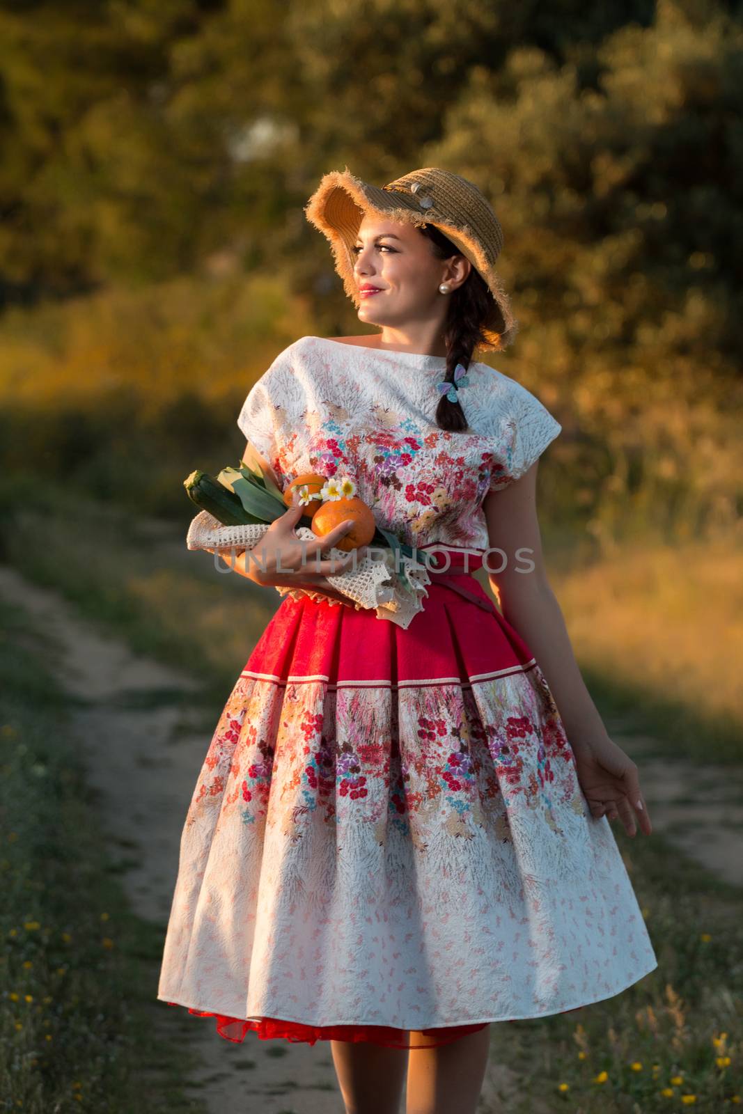 Vintage girl on the countryside with wicker hat gathering groceries.