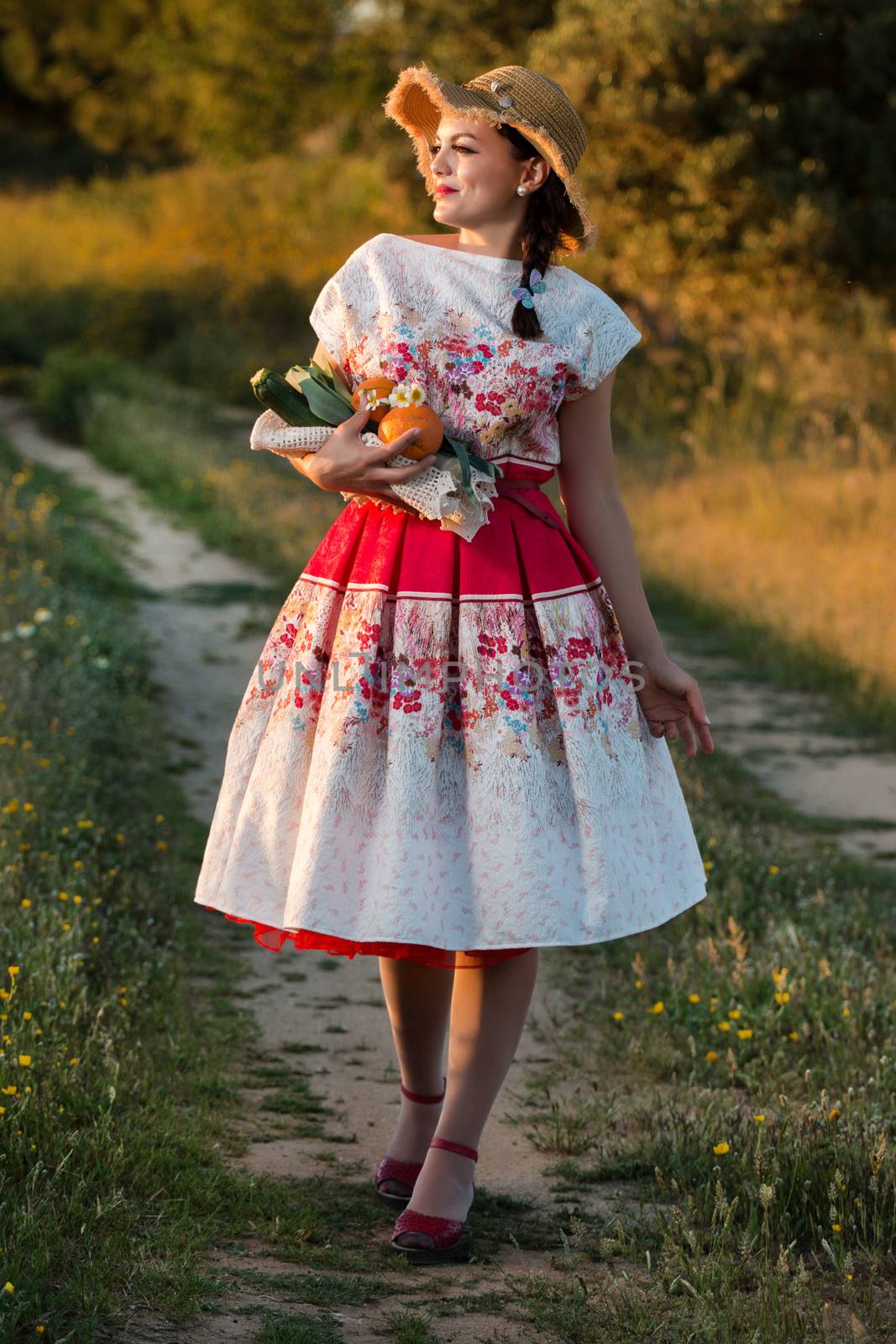 Vintage girl on the countryside with wicker hat gathering groceries.