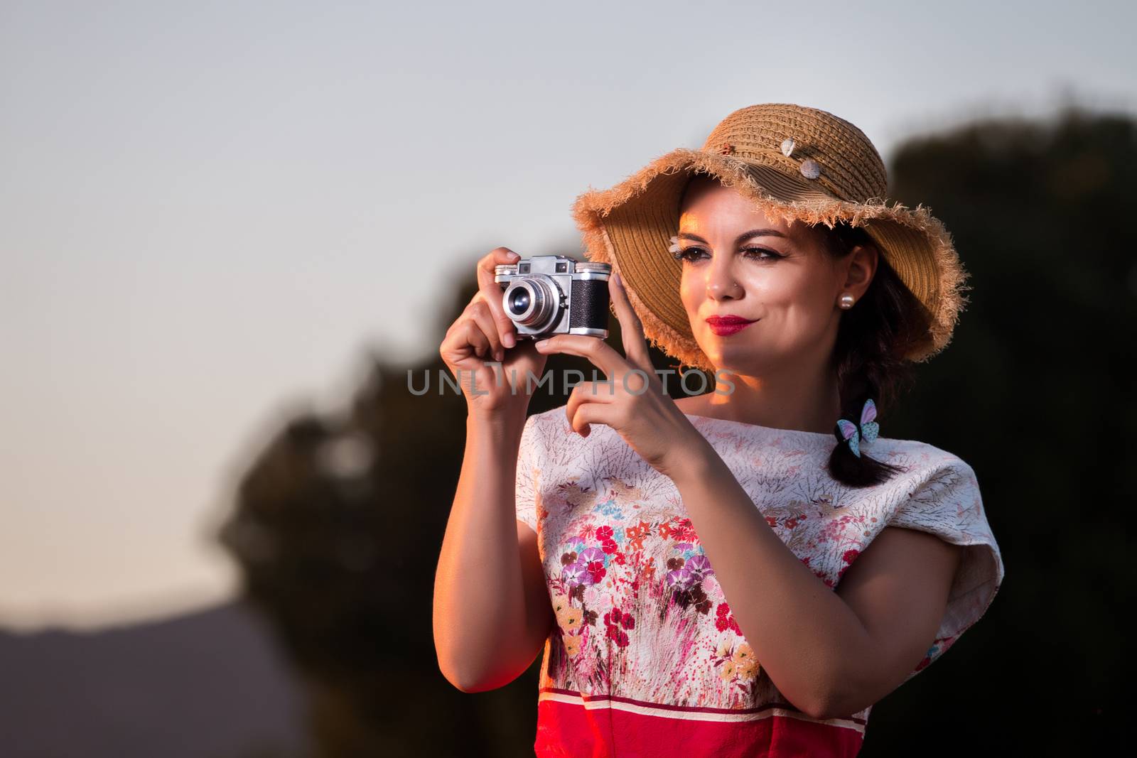 Vintage girl on the countryside with wicker hat with retro camera.