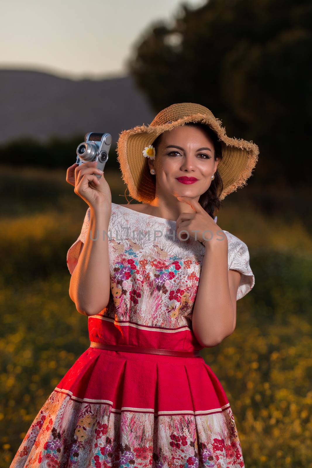 Vintage girl on the countryside with wicker hat with retro camera.