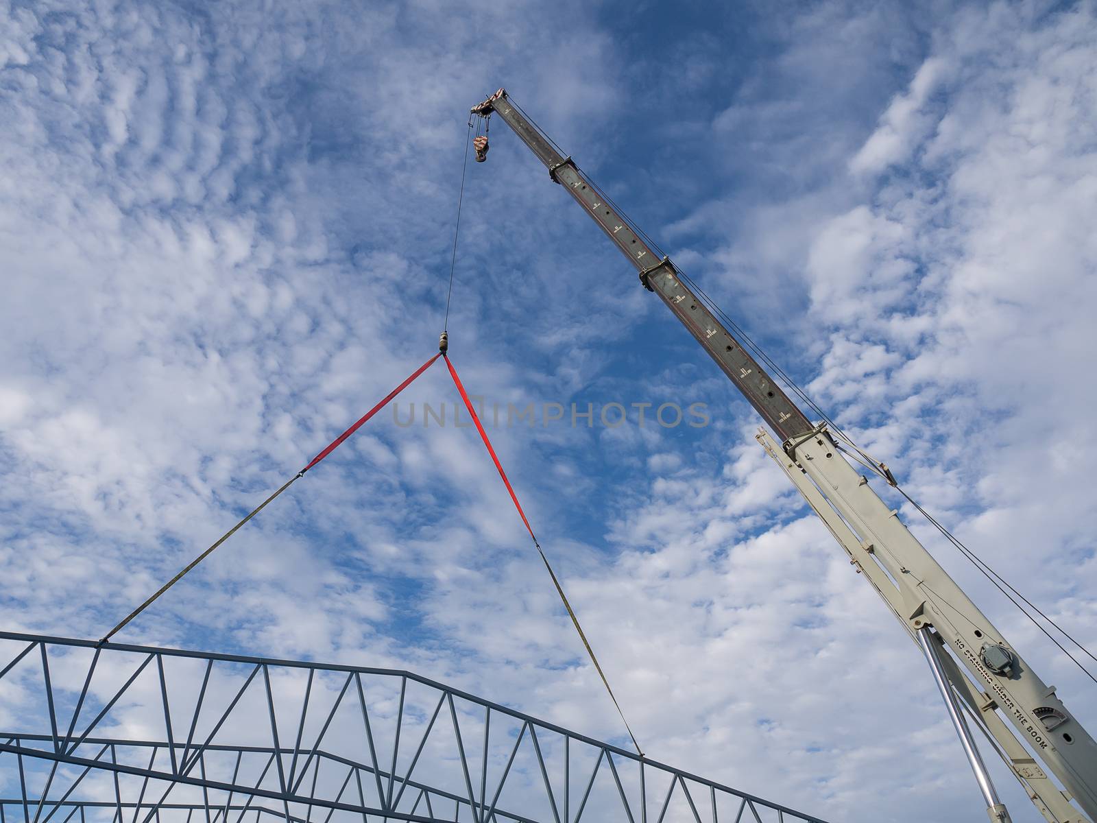 Mobile construction cranes with big tower cranes in sunny day with white clouds and deep blue sky on background, heavy industry.