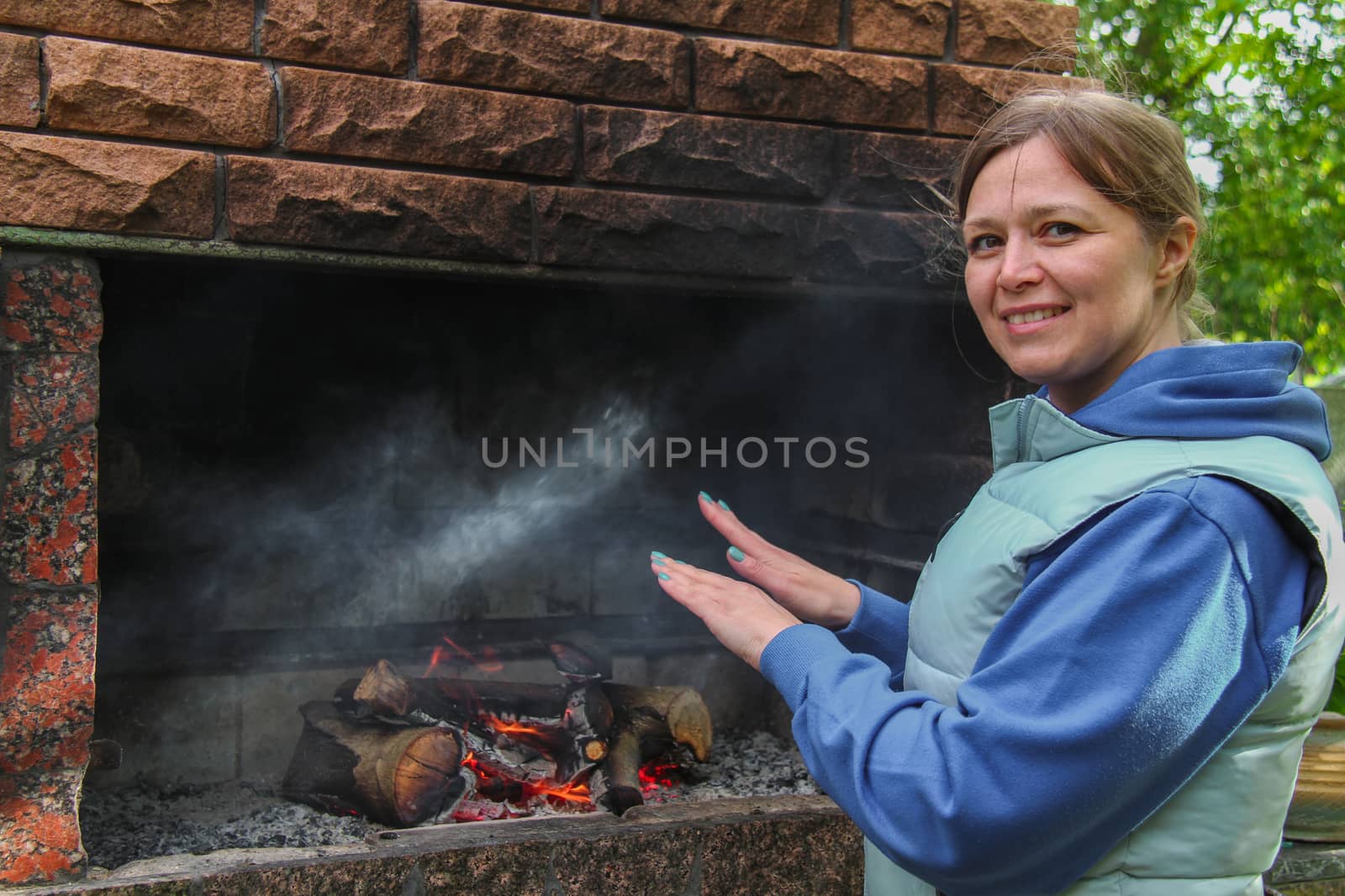 Woman warming hands near the fireplace at outdoor