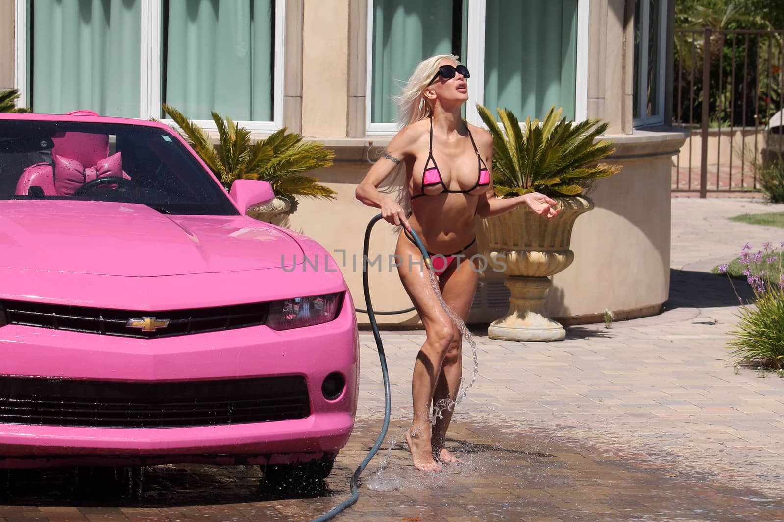 Frenchy Morgan the "Celebrity Big Brother" Star is spotted on a hot day wearing a tiny pink bikini while washing her pink car in Malibu, CA 05-22-17