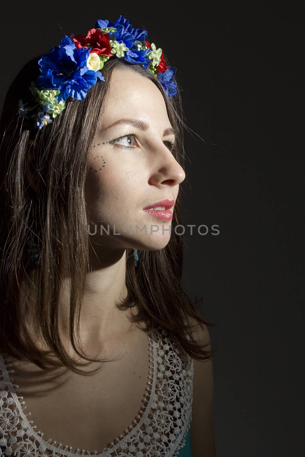 Portrait of a young woman in a wreath of flowers on a black background