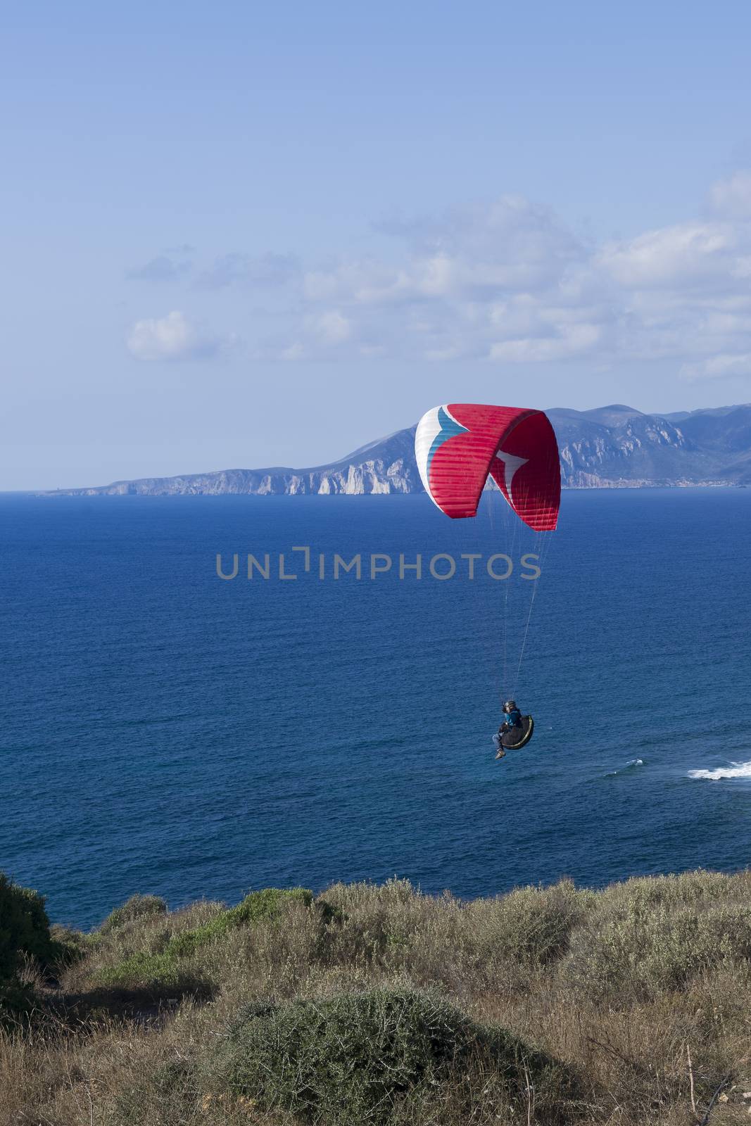 Colorful hang glider in sky over blue sea 