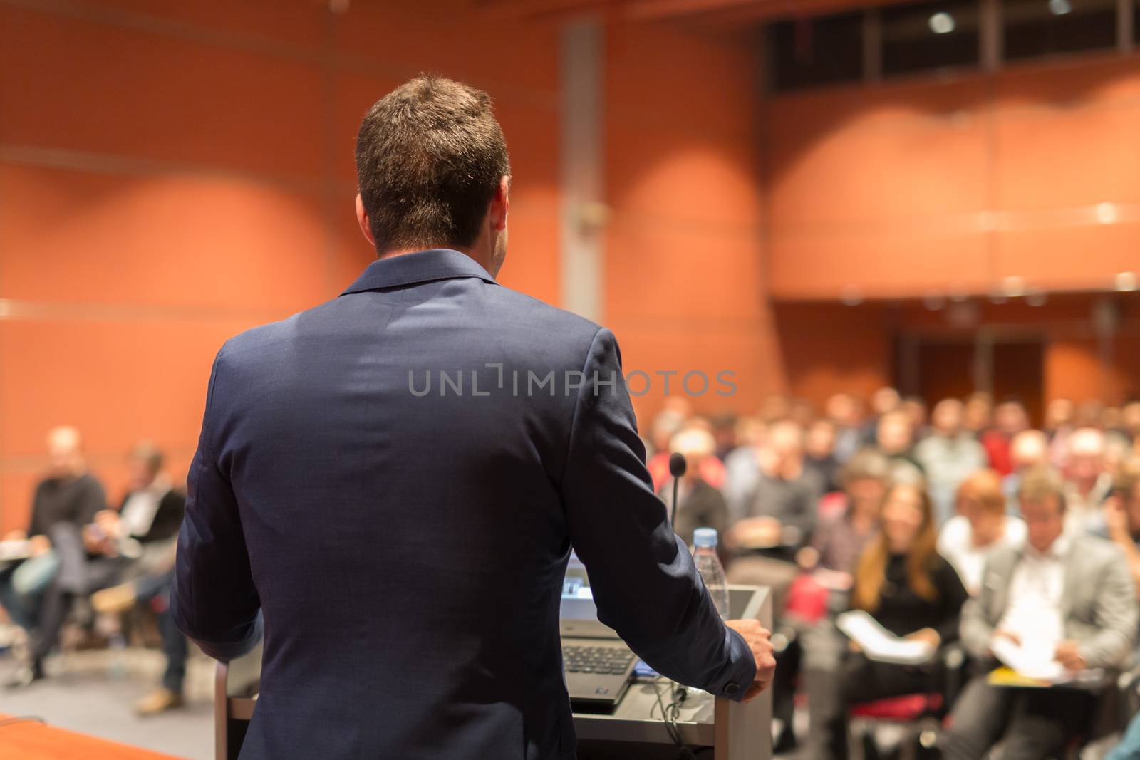 Speaker giving a talk on corporate Business Conference. Audience at the conference hall. Business and Entrepreneurship event.