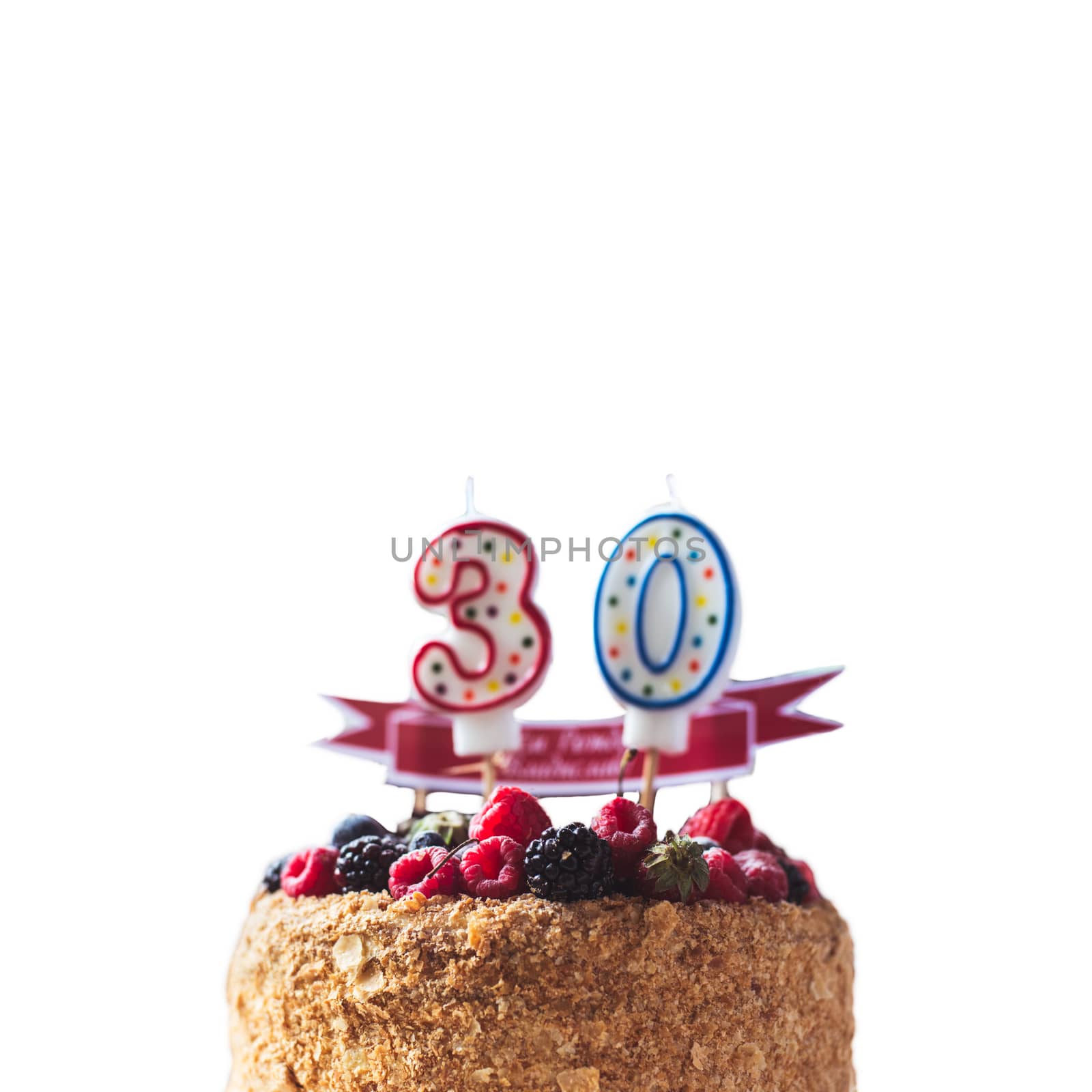 raspberries blackberry birthday cake with candles number 30 on white background and copyspace for your text.