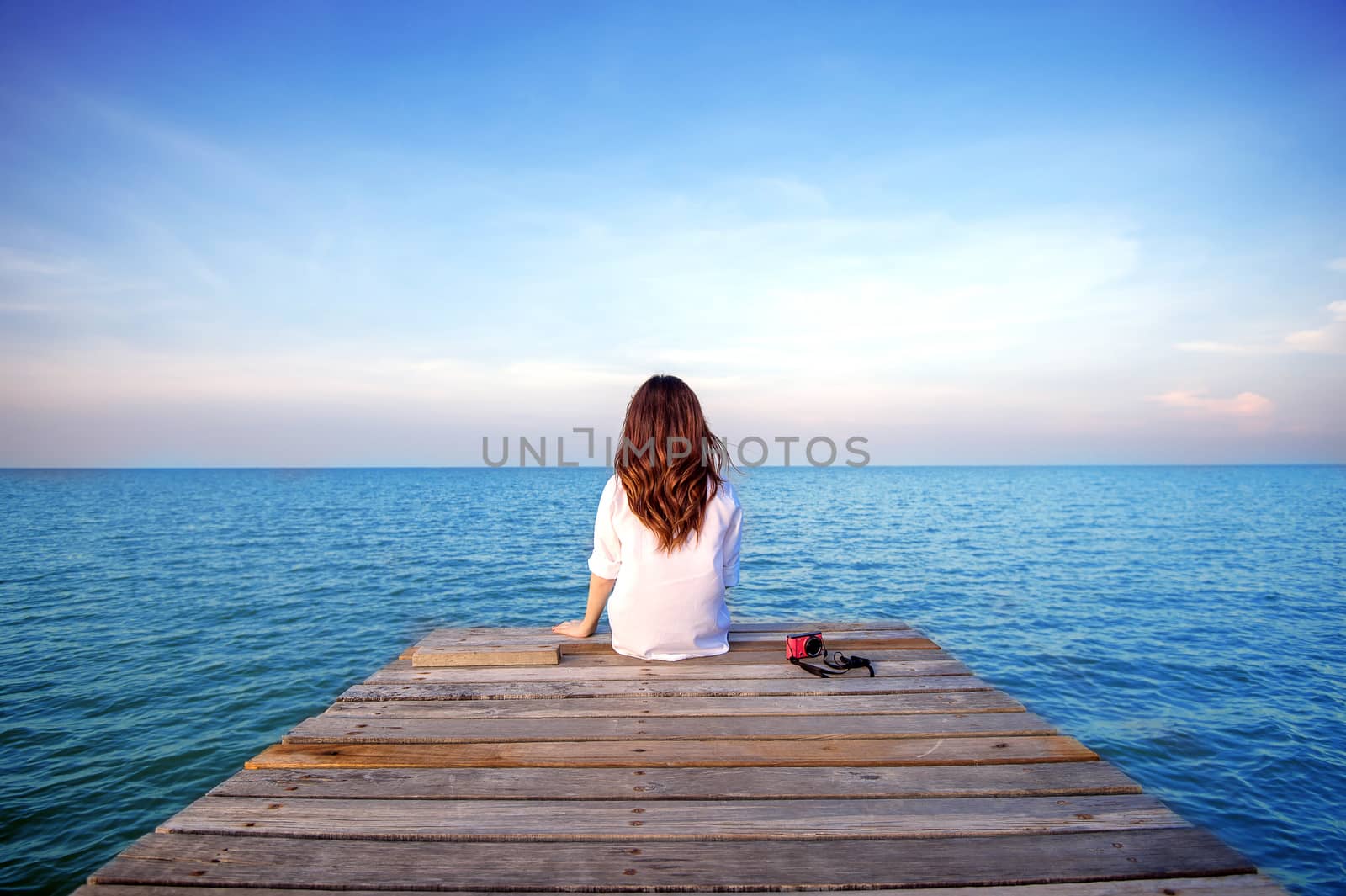 Girl sitting alone on a the wooden bridge on the sea. (frustrated depression)