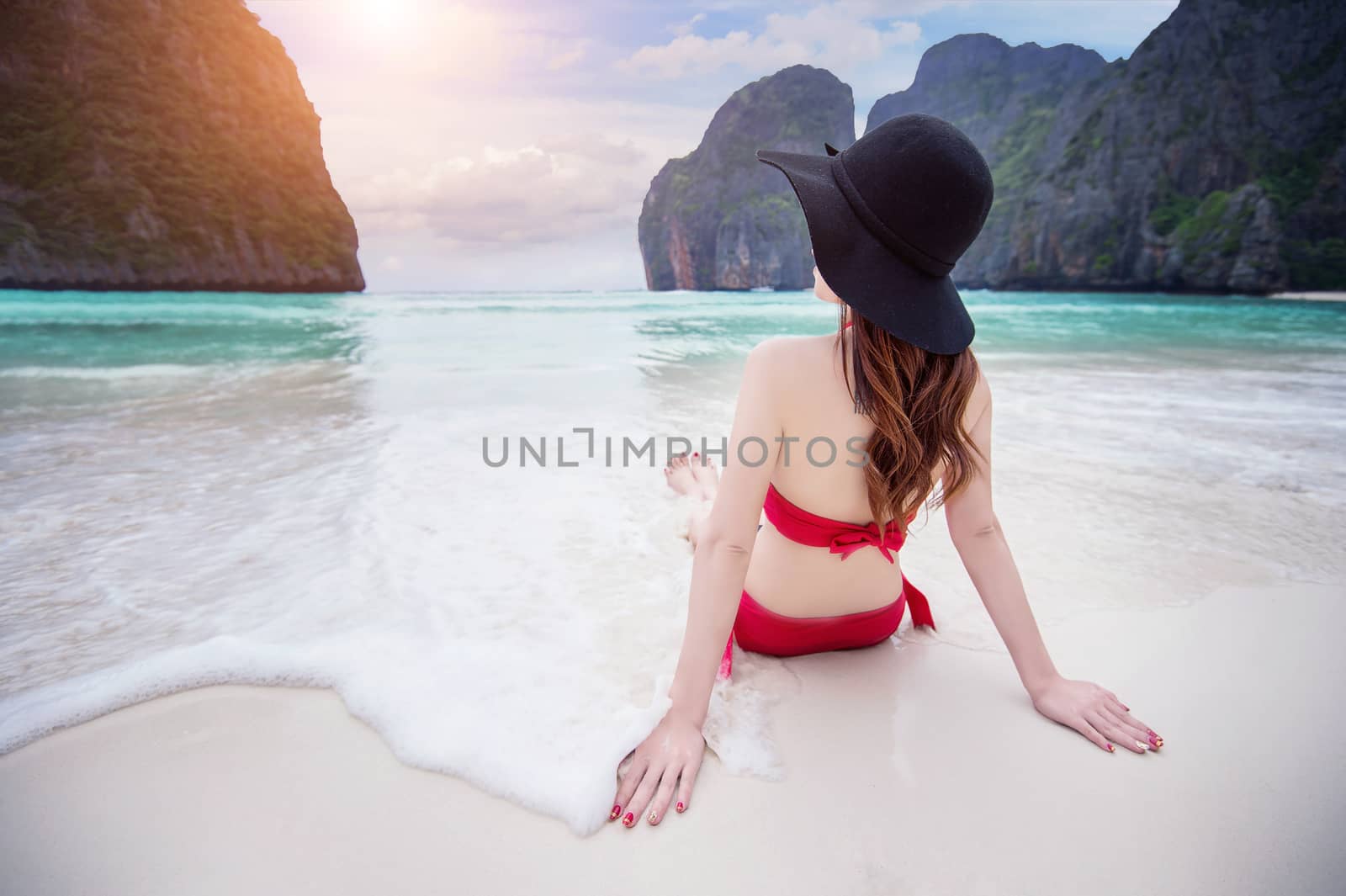 Young woman in red bikini sitting on the beach. by gutarphotoghaphy
