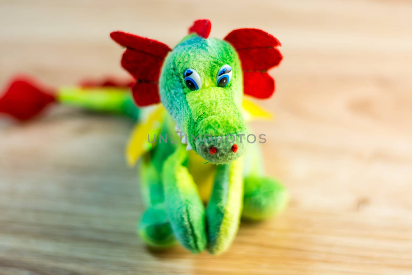 Knitted dragon isolated on wooden background by boys1983@mail.ru
