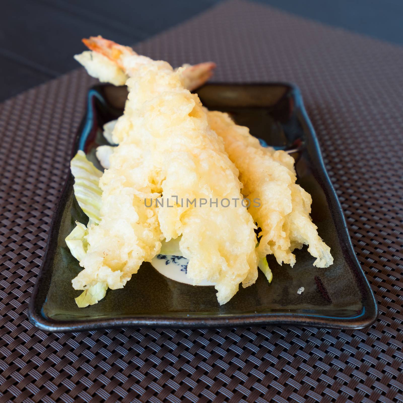 Japanese Cuisine,Tempura Shrimps (Deep Fried Shrimps) with sauce and vegetables on a black plate. Brown  background,shallow depth of field