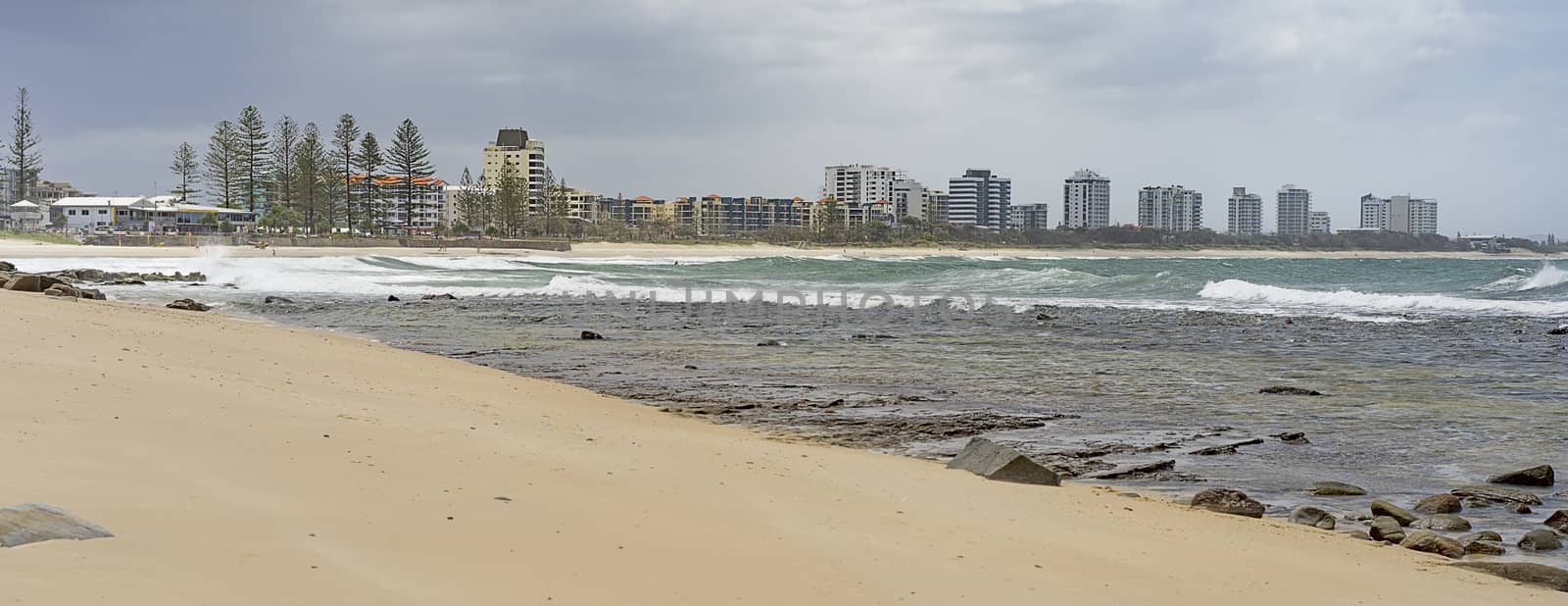 Panorama of Sunshine Coast foreshore at Alexandra Headlands Mooloolaba with surf, sand, rocky seafront and cloudy sky